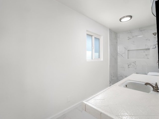 bathroom with marble finish floor, baseboards, and a sink