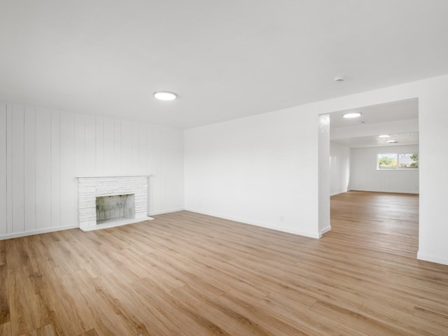 unfurnished living room featuring light wood finished floors, a fireplace, and baseboards