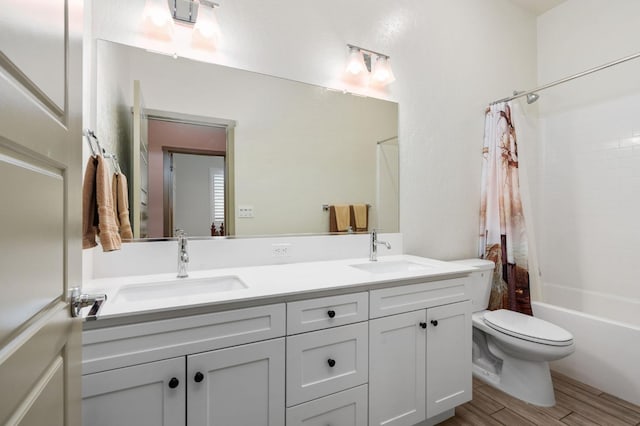 bathroom featuring double vanity, toilet, wood finished floors, and a sink