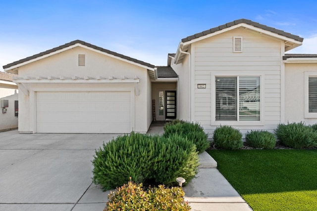 single story home with stucco siding, driveway, and a garage