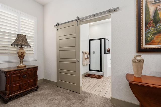 interior space featuring a barn door, baseboards, and carpet flooring