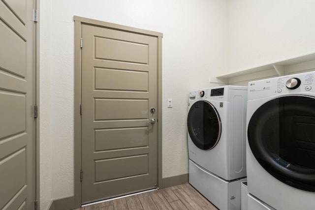 laundry room with washing machine and clothes dryer, laundry area, light wood finished floors, and baseboards