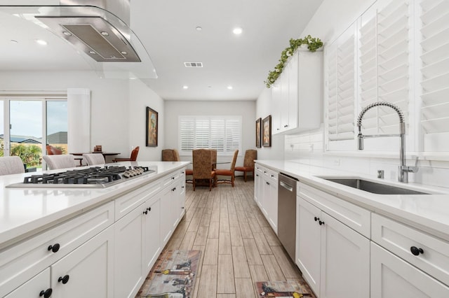 kitchen featuring visible vents, light wood-style floors, white cabinets, stainless steel appliances, and a sink