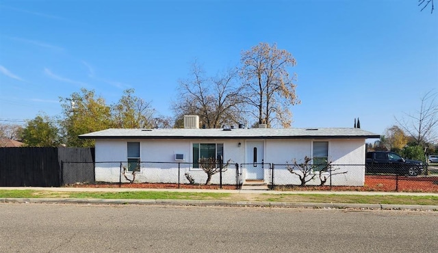 ranch-style house featuring a fenced front yard and stucco siding