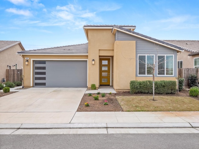 view of front of house with stucco siding, a garage, driveway, and fence