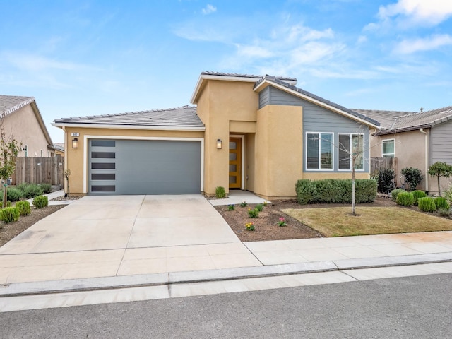 view of front facade featuring fence, a tile roof, concrete driveway, stucco siding, and an attached garage