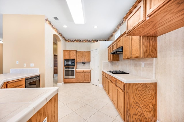 2565 Powers Ave, Clovis, CA 93619 - kitchen with light tile patterned floors, under cabinet range hood, visible vents, arched walkways, and black appliances