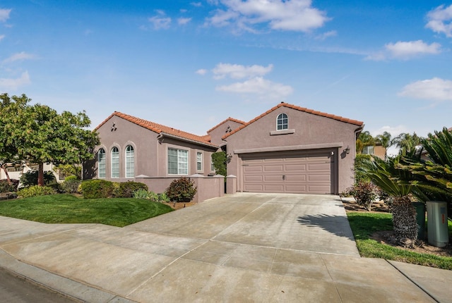 mediterranean / spanish home with a tile roof, concrete driveway, a front yard, stucco siding, and an attached garage