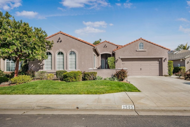 mediterranean / spanish-style house featuring stucco siding, a garage, concrete driveway, and a front lawn