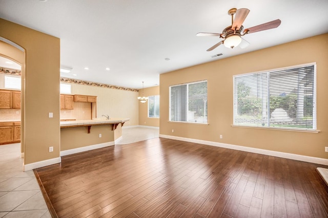 2565 Powers Ave, Clovis, CA 93619 - unfurnished living room featuring light wood-type flooring, ceiling fan with notable chandelier, baseboards, and visible vents