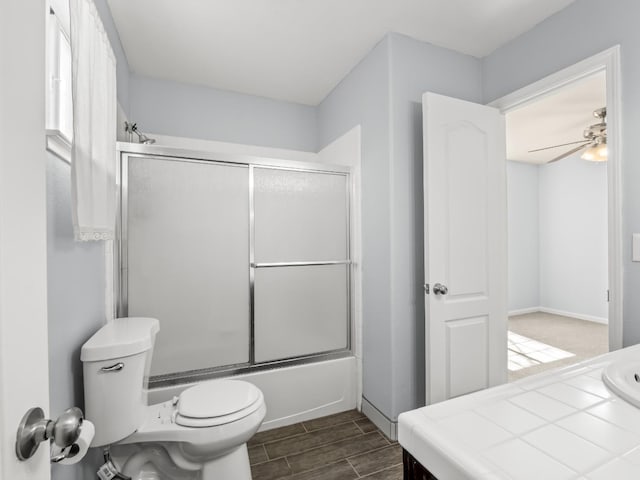 full bathroom featuring vanity, shower / bath combination with glass door, wood finish floors, ceiling fan, and toilet