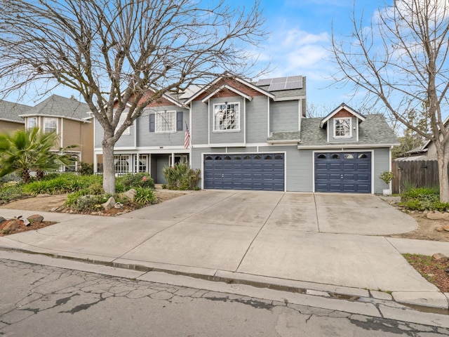 view of front of home with solar panels, a shingled roof, fence, concrete driveway, and a garage