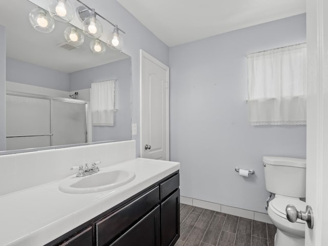 bathroom featuring vanity, baseboards, wood finish floors, a shower stall, and toilet