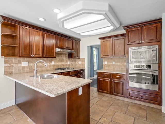 kitchen with a sink, under cabinet range hood, a peninsula, stainless steel appliances, and open shelves