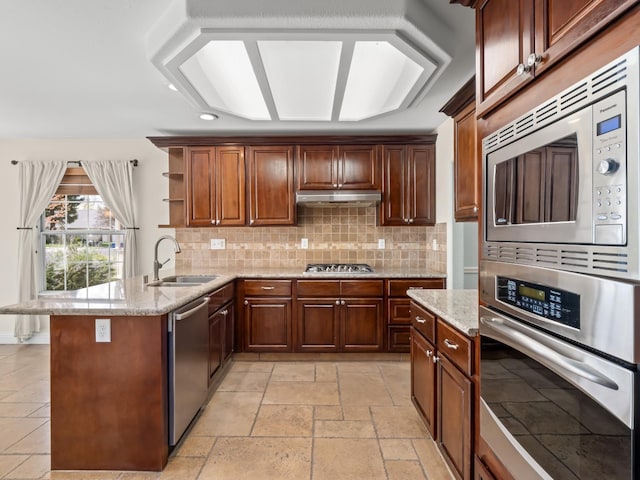 kitchen with stone tile floors, open shelves, a sink, stainless steel appliances, and under cabinet range hood