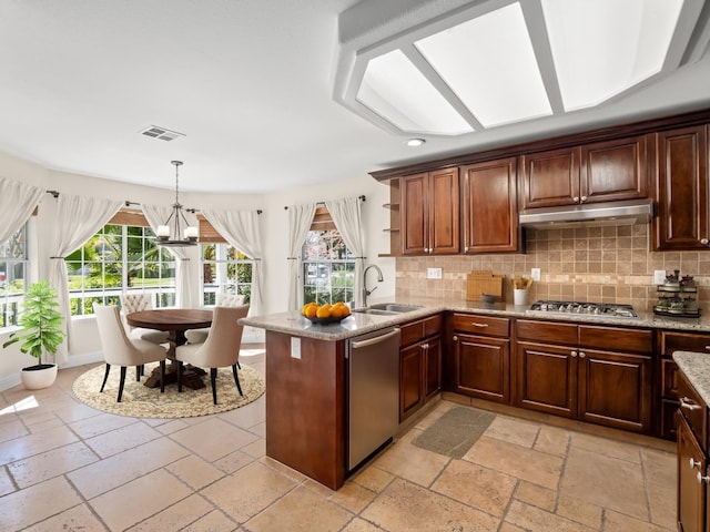 kitchen with visible vents, under cabinet range hood, stone tile floors, stainless steel appliances, and a sink