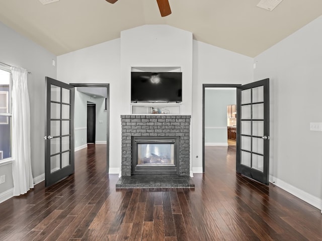 unfurnished living room featuring french doors, a brick fireplace, wood finished floors, and vaulted ceiling