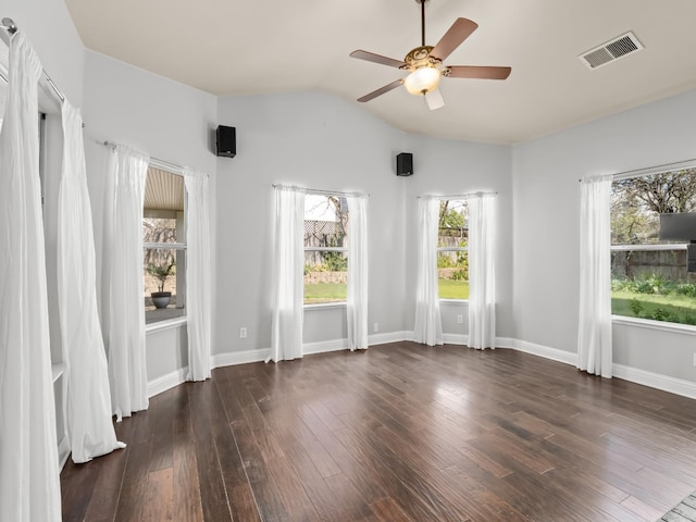 spare room featuring dark wood-style floors, visible vents, baseboards, lofted ceiling, and ceiling fan