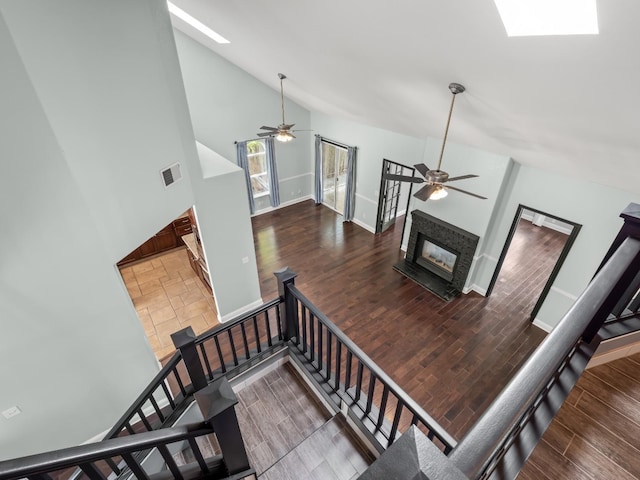 staircase with a skylight, visible vents, high vaulted ceiling, and wood finished floors