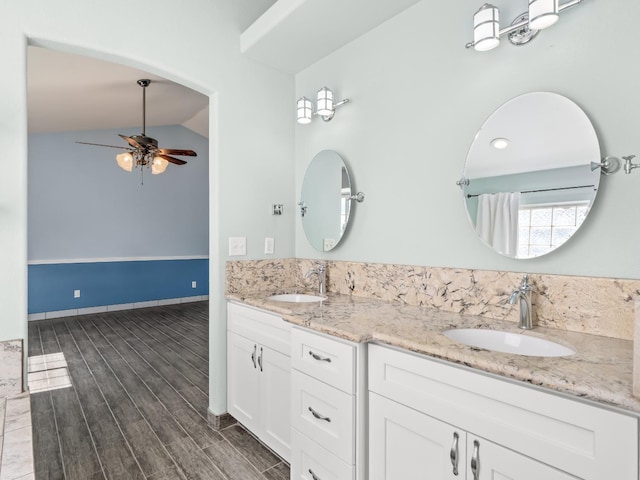 bathroom with wood tiled floor, double vanity, lofted ceiling, and a sink