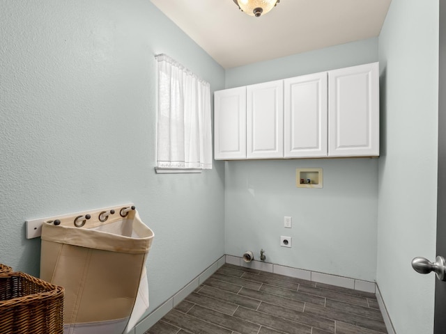 clothes washing area featuring electric dryer hookup, wood finish floors, washer hookup, hookup for a gas dryer, and cabinet space