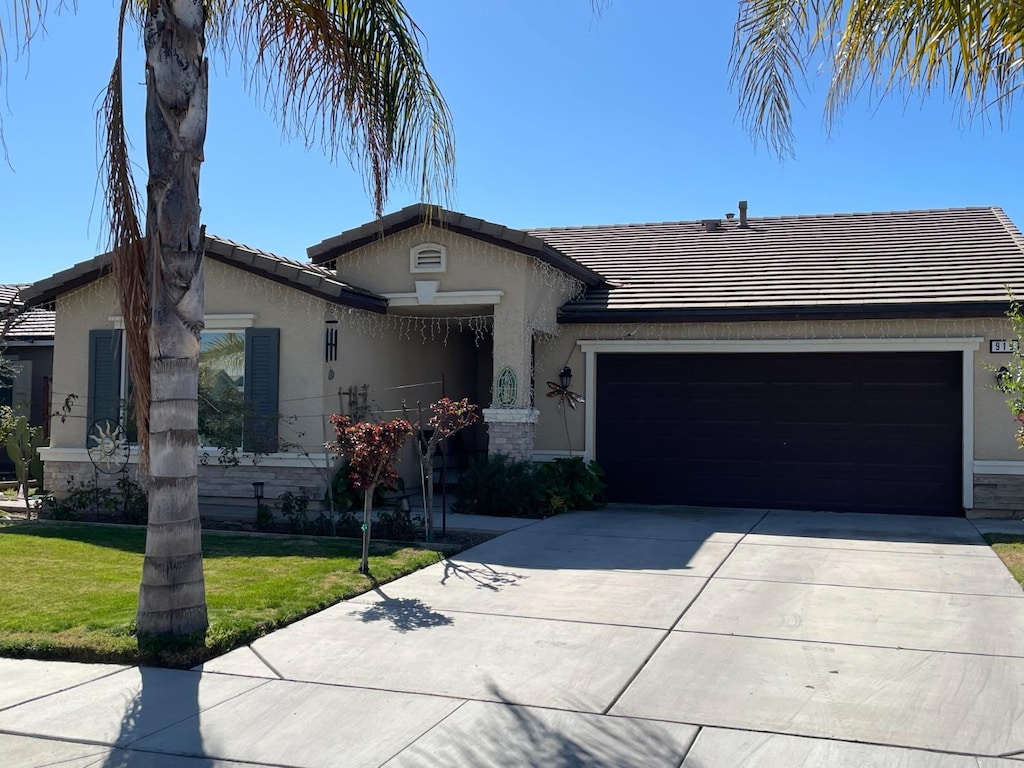 ranch-style home featuring stucco siding, a front yard, a garage, and driveway