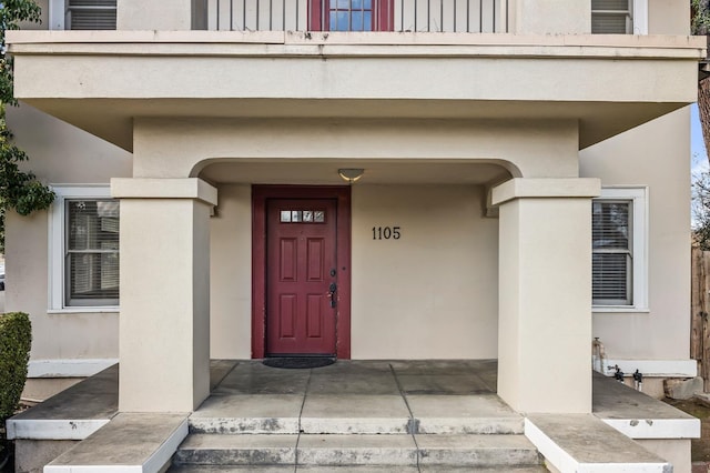 property entrance featuring a balcony, board and batten siding, and stucco siding