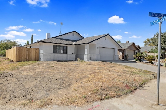 ranch-style home with an attached garage, fence, brick siding, and driveway