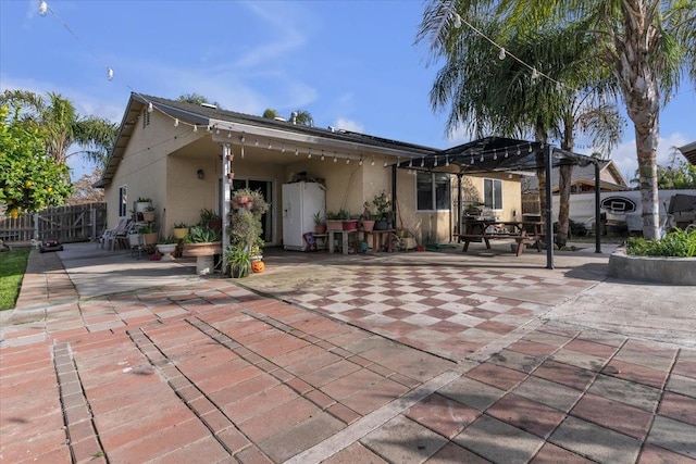 back of property with stucco siding, a patio, a pergola, and fence