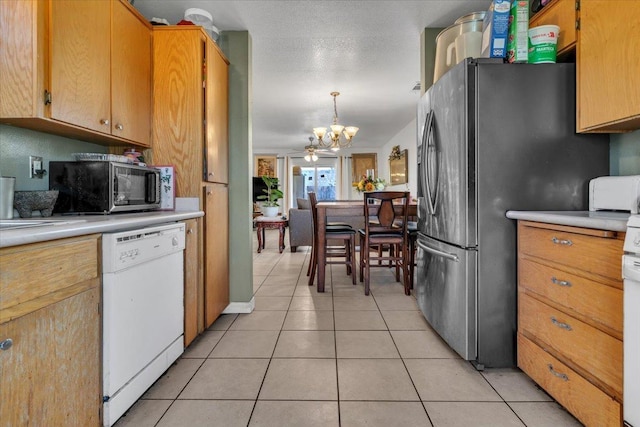 kitchen featuring light countertops, appliances with stainless steel finishes, light tile patterned flooring, a notable chandelier, and a textured ceiling