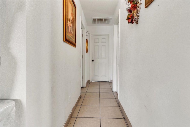 corridor featuring light tile patterned floors, visible vents, and baseboards