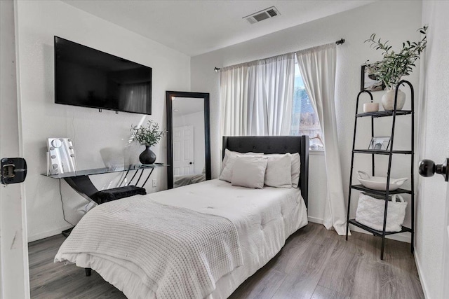 bedroom featuring visible vents, baseboards, and wood finished floors