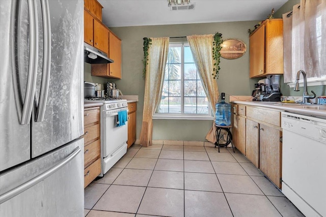 kitchen featuring under cabinet range hood, a sink, white appliances, light tile patterned flooring, and light countertops