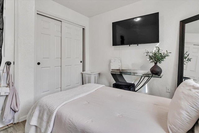 bedroom with wood finished floors and a closet