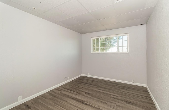 unfurnished room with a paneled ceiling, dark wood-type flooring, and baseboards