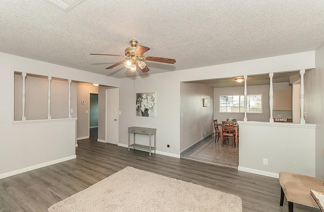 interior space with a ceiling fan, visible vents, wood finished floors, baseboards, and a textured ceiling