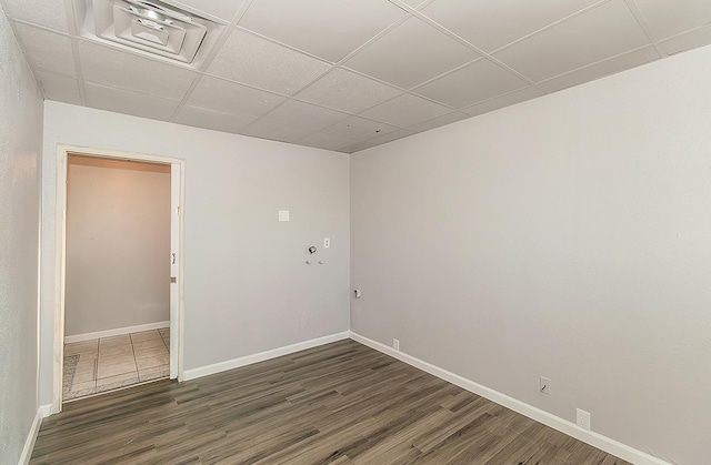 spare room with a drop ceiling, baseboards, visible vents, and wood finished floors