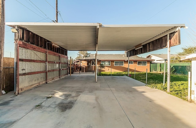 view of parking / parking lot with an attached carport and fence