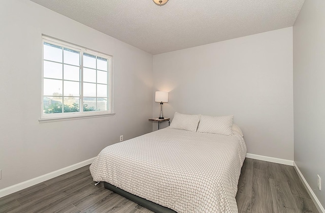 bedroom featuring a textured ceiling, baseboards, and wood finished floors