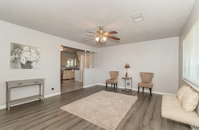 living area with wood finished floors, baseboards, visible vents, washing machine and clothes dryer, and a textured ceiling