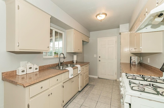 kitchen with light tile patterned floors, baseboards, white range with gas stovetop, a sink, and under cabinet range hood