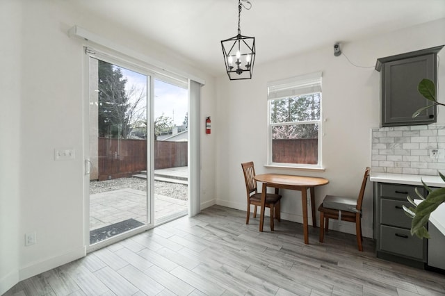 dining space with light wood finished floors, an inviting chandelier, and baseboards