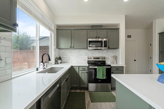 kitchen with decorative backsplash, light countertops, appliances with stainless steel finishes, and a sink