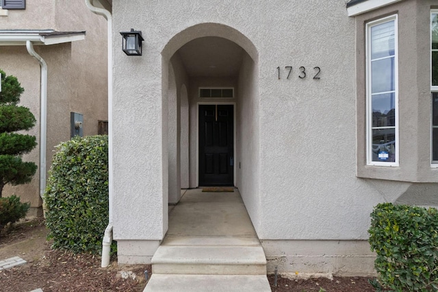 entrance to property with visible vents and stucco siding