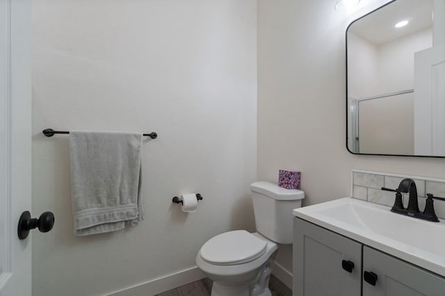 bathroom with decorative backsplash, baseboards, toilet, and vanity