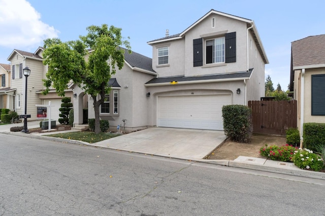 traditional-style house with stucco siding, driveway, an attached garage, and fence