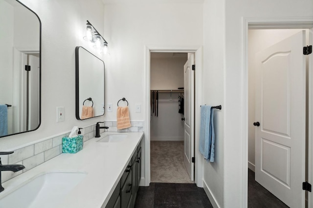 bathroom featuring double vanity, a spacious closet, and a sink