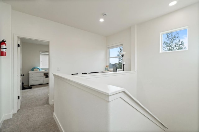 hall with recessed lighting, an upstairs landing, light colored carpet, and baseboards