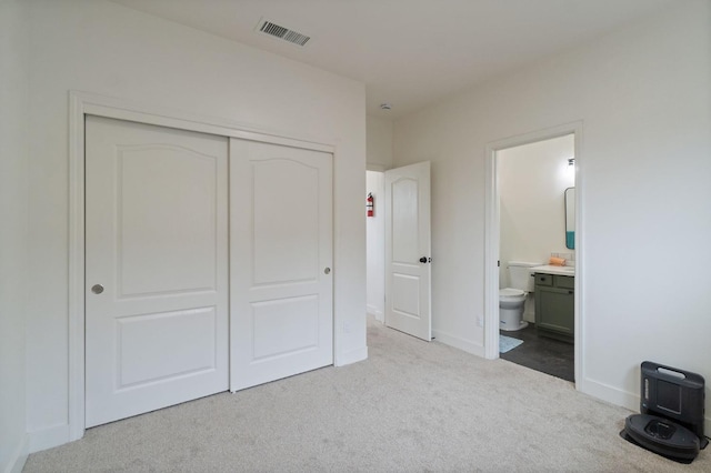 unfurnished bedroom with visible vents, baseboards, carpet, ensuite bathroom, and a closet