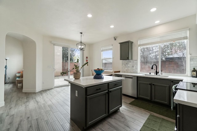 kitchen featuring tasteful backsplash, dishwasher, light countertops, arched walkways, and a sink